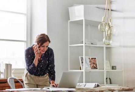 Photo: Woman working on phone and laptop