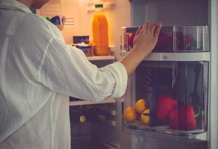 Photo: Adult reaching into fridge at night